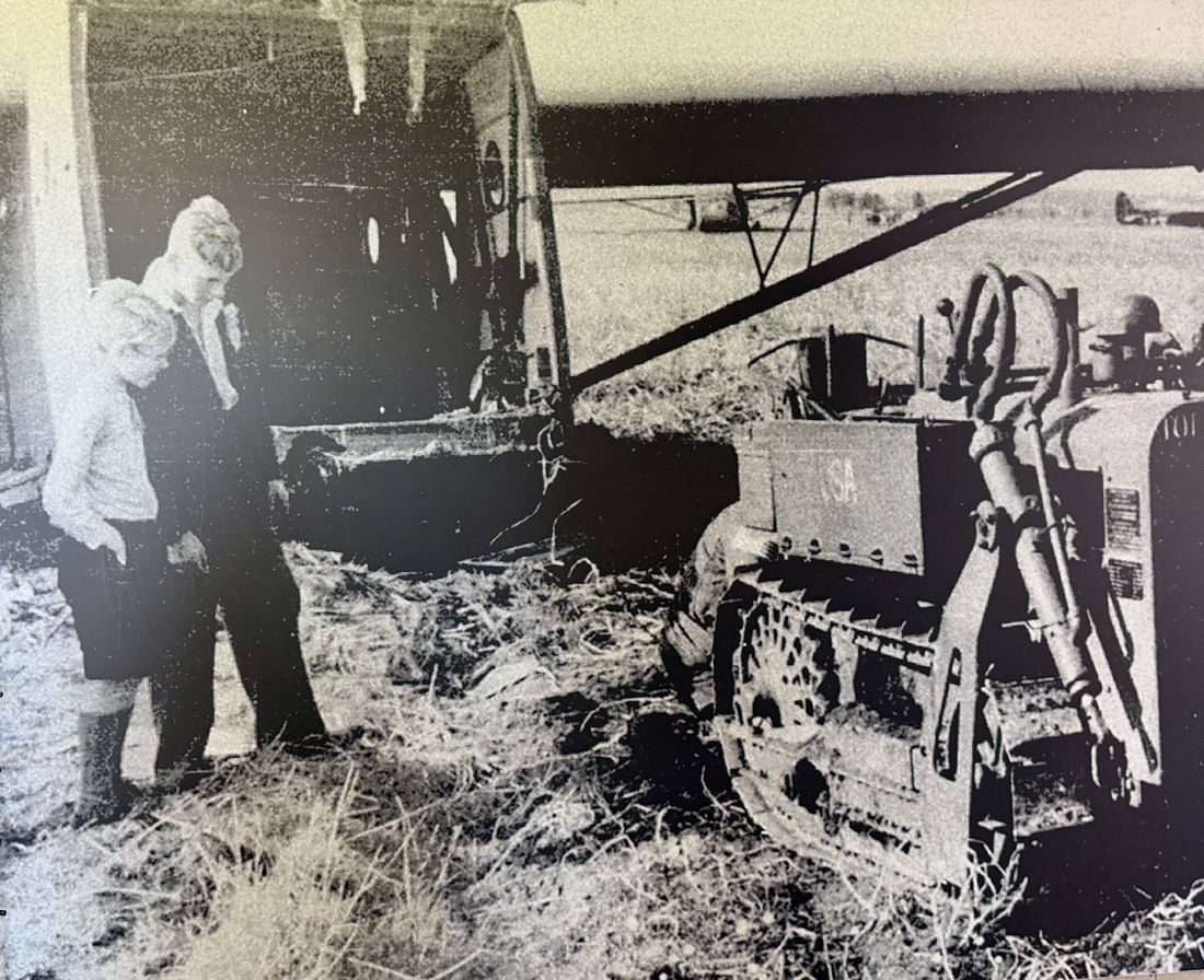 Children beside an aircraft and a farm tractor in a field