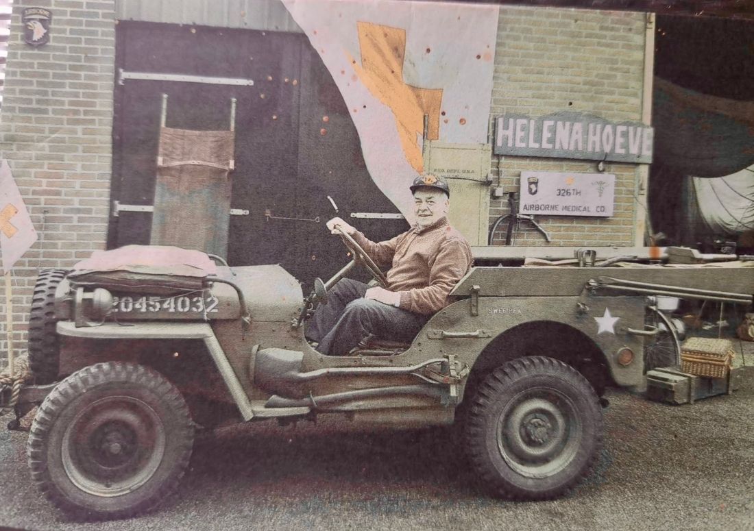 A man in an American jeep outside a farm building signed Helena Hoeve