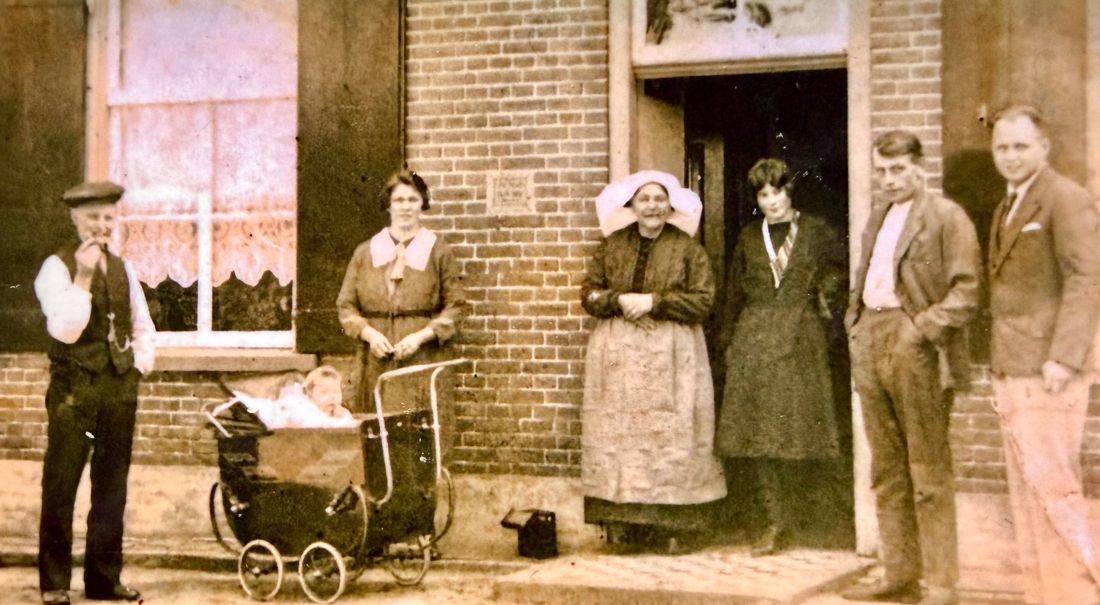 Family members outside a brick house with a pram