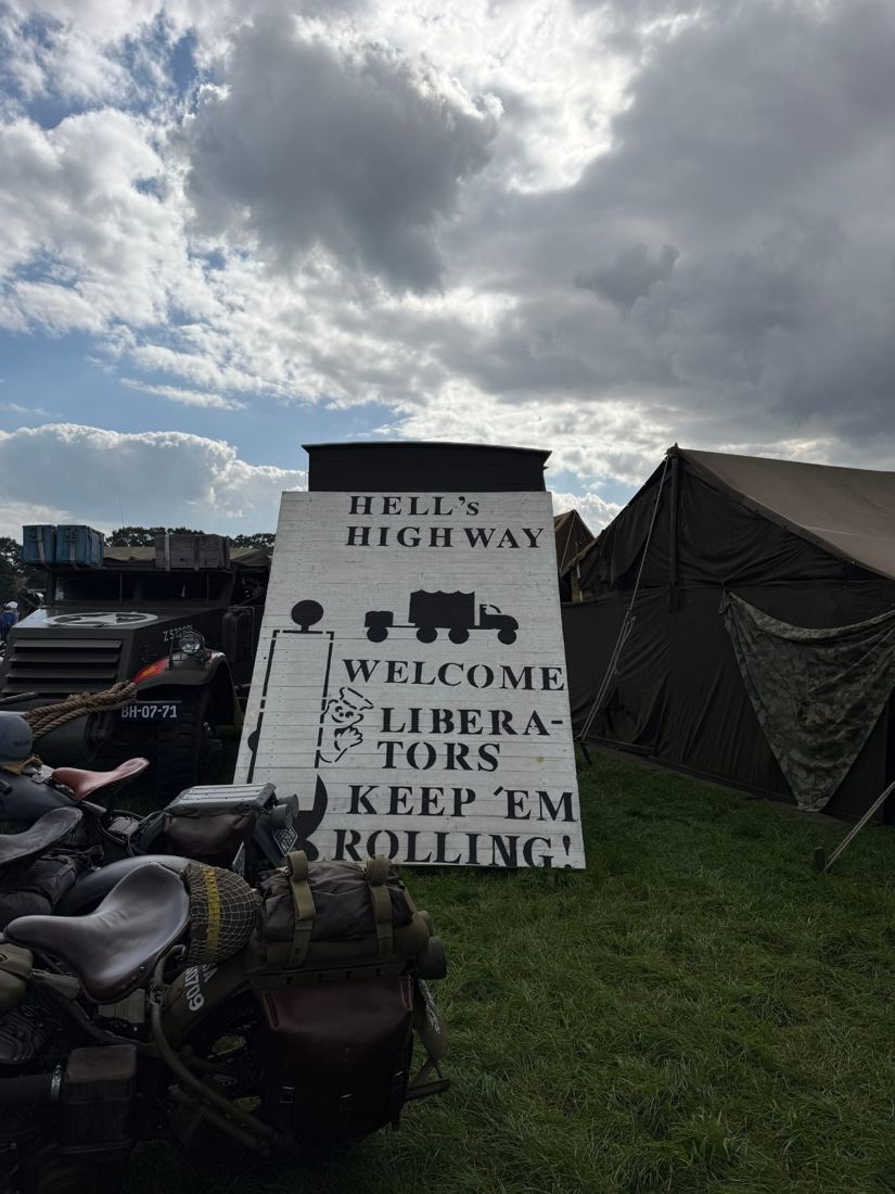 Hand-painted sign at Camp Liberty reading Hell's Highway, Welcome Liberators, Keep 'em Rolling