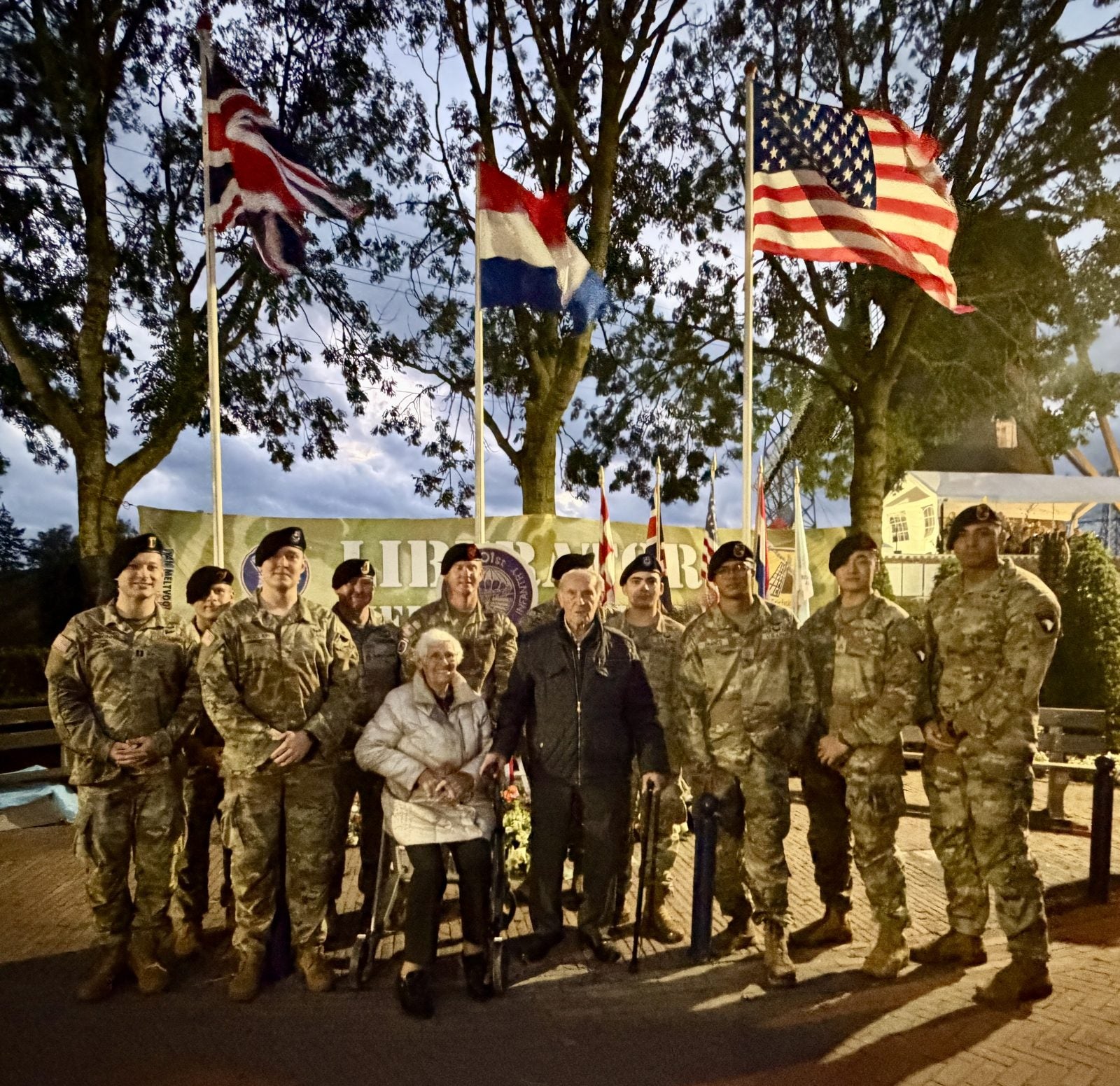 Adriaan van Hooft and his wife with soldiers of the 101st Airborne beneath British, Dutch and American flags
